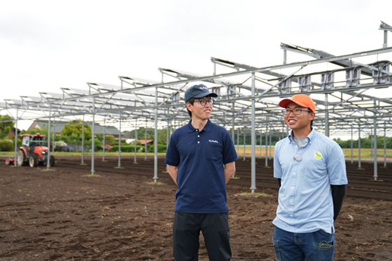 太陽光パネルが設置されたほ場で、農地の2階建ての可能性について語り合う谷さん(左)と小林さん(右)