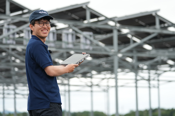 営農型太陽光発電の前で笑顔を見せる谷さん