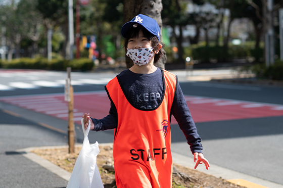 クボタスピアーズのビブスを着て、街の清掃活動に参加する男の子
