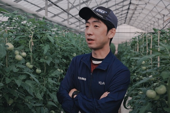 トマトを栽培しているビニルハウス内でインタビューに答えている農事組合法人 濁川生産組合 代表理事の田村雄太郎さん
