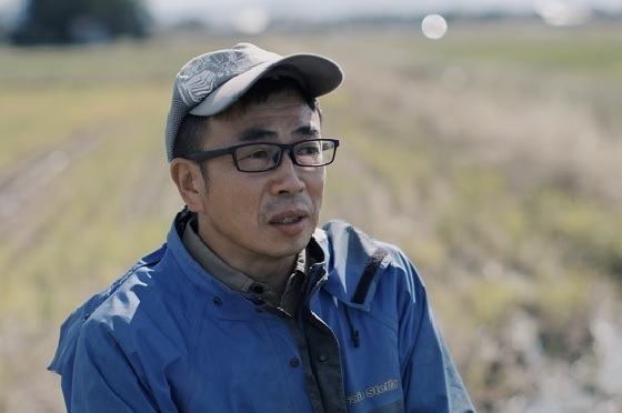 ほ場で若いスタッフの頼もしさを語る濁川生産組合 理事の大塚克洋さん