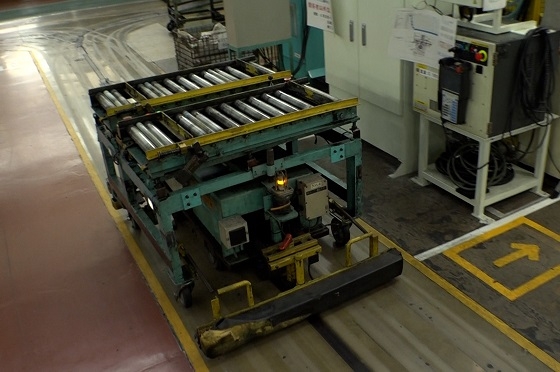 工場内の床に埋め込まれている誘導路上を動いて部品を運ぶAGV（無人搬送車）