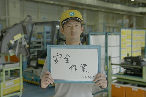 自身が仕事で心がけていることをボードに「安全作業」と書いて体の前に掲げる谷口翔さん