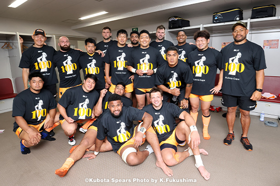 ロッカールームで、杉本博昭選手のチーム100キャップを祝うTシャツを着用しながら、記念写真におさまるクボタスピアーズのチームメンバー