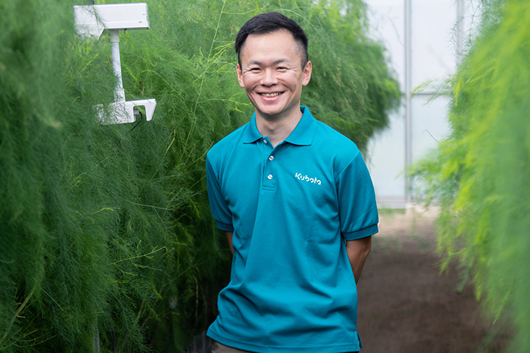 アスバラガスを栽培しているビニールハウスの中で微笑む萩本誠晃さん