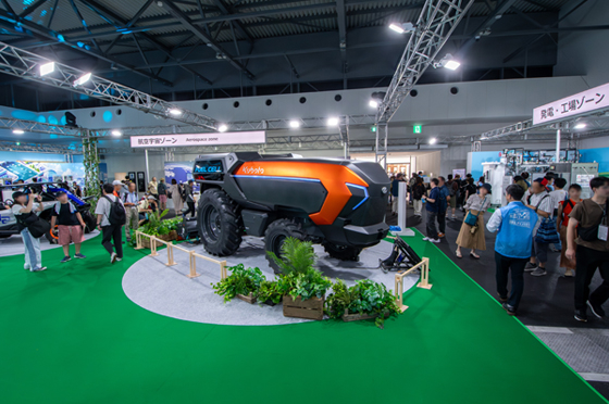 会場の中央に配置されたクボタオレンジのオートノマスFCトラクタを見学する人々