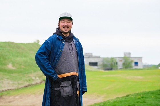 北海道厚真町の自社牧場を背に立つGOOD GOODの河合祥太さん