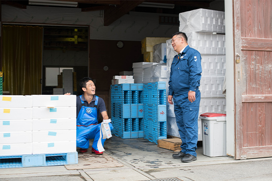 岩手県釜石市の平田地区にあるヤマキイチ商店の倉庫にて、専務の君ヶ洞剛一さんと笑顔で語り合う青木健一さん