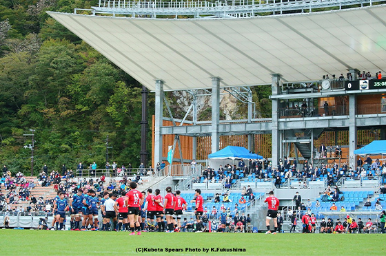 2020年10月10日、釜石鵜住居復興スタジアムで開催されたラグビーメモリアルマッチ、釜石シーウェイブスとクボタスピアーズによる試合のワンシーン。ひとつのボールをめぐって、赤いジャージの釜石シーウェイブスと水色のジャージのクボタスピアーズの選手らが入り乱れています。