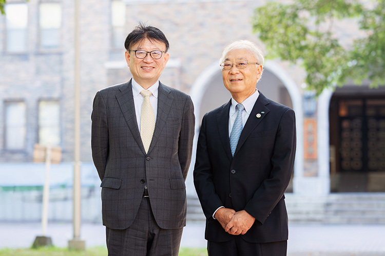 北海道大学農学部の校舎前で写真に収まる北海道大学・野口伸教授とクボタ・飯田聡特別技術顧問