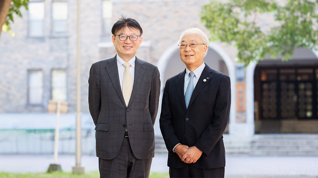 北海道大学農学部の校舎前で写真に収まる北海道大学・野口伸教授とクボタ・飯田聡特別技術顧問